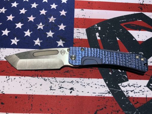 The Slim Midi Marauder S35VN Tanto Blade Blue Ano Water Ripple Sculpted Handles on top of an american flag.