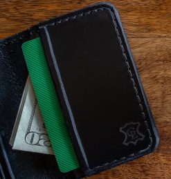 Grommet's Leathercraft Bernie Bi-Fold Black Leather Wallet with a credit card and money sticking out of it.