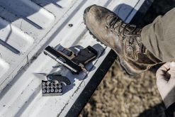 A pair of Zero Tolerance 0022 20CV Blade Titanium/Carbon Fiber Handle boots and a gun on a bench.