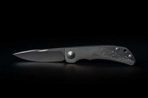 A Chris Reeve Knives Impinda "The Climb" slip joint knife with a titanium handle and CAD engraving on a black background.