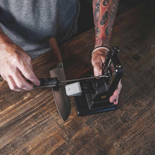 A man with a Work Sharp - Precision Adjust Sharpener with Tri-Brasive tattoo on his arm working on a piece of wood.