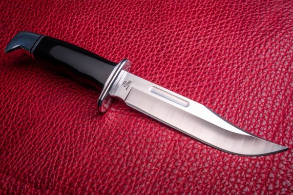 a knife on a red cloth with a black handle.